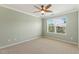 This cozy bedroom features neutral carpeting, a ceiling fan, and a bright window at 2128 Feather Ridge Dr, Holly Springs, NC 27540