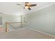 Upstairs landing with neutral carpet, ceiling fan, and stairway with wooden railing at 2128 Feather Ridge Dr, Holly Springs, NC 27540