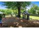 Wooden backyard deck with a railing and mature tree, providing shade and a play structure at 2417 Ridgeford Ct, Fuquay Varina, NC 27526