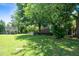 Large backyard featuring a deck, mature trees, and a covered structure, perfect for outdoor activities and relaxation at 2417 Ridgeford Ct, Fuquay Varina, NC 27526