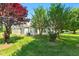 Serene backyard with established trees, a vibrant lawn, and partial view of home's light-colored siding at 3027 Maple Ave # A-1, Burlington, NC 27215