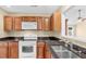 Kitchen featuring dark countertops, wooden cabinets, stainless steel sink, and white appliances at 3027 Maple Ave # A-1, Burlington, NC 27215