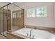 A modern bathroom with a tiled shower, large tub, and window, providing a relaxing and bright space at 309 Larkhaven Pl, Apex, NC 27539
