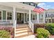 Inviting front porch features a classic design with white columns, brick steps, and manicured landscaping for added appeal at 309 Larkhaven Pl, Apex, NC 27539