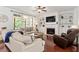 Bright living room featuring a fireplace, built-in shelves, hardwood floors, and lots of natural light at 309 Larkhaven Pl, Apex, NC 27539