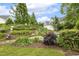 Beautiful landscaped backyard showcasing a variety of plants, trees, and shrubs under a blue sky at 309 Plank Bridge Way, Morrisville, NC 27560