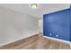Bedroom with blue accent wall, wood look flooring, a ceiling light and an ensuite bathroom at 3449 S Beaver Ln, Raleigh, NC 27604