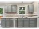 Close-up of the kitchen sink area, featuring gray cabinets, stainless steel appliances, and a window at 366 E Smithfield St, Angier, NC 27501