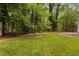 Lush backyard featuring a well-manicured lawn, surrounded by mature trees and green foliage at 4004 Bamburgh Ln, Apex, NC 27539