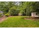 Spacious backyard featuring lush green grass, mature trees, and charming outbuildings at 4004 Bamburgh Ln, Apex, NC 27539