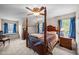 Bedroom featuring a four-poster bed, blue curtains, two windows, and a ceiling fan at 4024 Rural Retreat Rd, Burlington, NC 27215