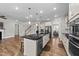 Open kitchen with island, stainless steel appliances, and hardwood floors at 408 Torwood Cir, Apex, NC 27523