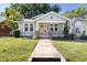 Charming single-story home featuring a quaint front porch, bright yellow door, and beautifully maintained yard at 409 N Hyde Park Ave, Durham, NC 27703