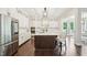 Gourmet kitchen showcasing white cabinets, stainless steel refrigerator, island with seating, and wood flooring at 421 Gilpin Way, Cary, NC 27519