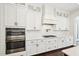 Modern kitchen features built-in ovens, white cabinets, sleek hardware, and a tiled backsplash for a modern aesthetic at 421 Gilpin Way, Cary, NC 27519