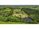 An aerial view of a property featuring a house, pond, large grassy area, and surrounding forest at 5200 Mrs Fuller Rd, Mebane, NC 27302