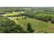 Wide aerial view of rolling green fields, tree coverage and home featuring an outdoor swimming pool at 5200 Mrs Fuller Rd, Mebane, NC 27302