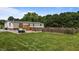 Large backyard with a wooden deck, privacy fence, lush grass, and mature trees at 5200 Mrs Fuller Rd, Mebane, NC 27302