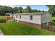 View of the home's side and backyard, featuring a wooden deck and lush green lawn at 5200 Mrs Fuller Rd, Mebane, NC 27302