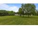 View of the property's green front yard with large trees and a house in the background on a sunny day at 5200 Mrs Fuller Rd, Mebane, NC 27302