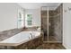 Well-lit bathroom featuring a soaking tub with a tiled surround and a tiled glass-enclosed shower at 5942 Big Nance Dr, Raleigh, NC 27616