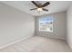 A neutral bedroom featuring a large window, carpet, ceiling fan with light, and neutral walls at 5942 Big Nance Dr, Raleigh, NC 27616