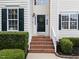 Charming front door with a decorative wreath, brick steps, and manicured bushes at 5942 Big Nance Dr, Raleigh, NC 27616