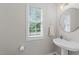 Half bathroom with a pedestal sink, a round mirror and a window at 5942 Big Nance Dr, Raleigh, NC 27616