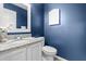Stylish powder room with blue walls, granite vanity, and framed mirror at 6104 New Market Way, Raleigh, NC 27609