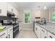 Charming kitchen featuring white cabinetry, granite counters, and stainless steel appliances at 6104 New Market Way, Raleigh, NC 27609
