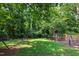 Lush backyard boasts a trampoline, a cozy firepit area, and a wooden playset, creating a fun outdoor retreat at 7009 Brecken Ridge Ave, Raleigh, NC 27615