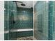 Modern bathroom shower features rain shower head and a tiled bench, with beautiful green tiling and glass door at 7009 Brecken Ridge Ave, Raleigh, NC 27615