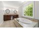 Bathroom featuring double sinks, a jacuzzi bathtub, and natural lighting with lots of space at 7009 Brecken Ridge Ave, Raleigh, NC 27615
