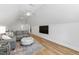 Bonus room with a TV, grey sofa, ottoman, and hardwood floors at 911 Canterbury Rd, Raleigh, NC 27607