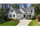 Charming white home with a black roof, lush landscaping, and an attached garage at 911 Canterbury Rd, Raleigh, NC 27607