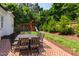 Beautiful backyard brick patio with a dining table set, surrounded by green landscaping, perfect for outdoor entertaining at 911 Canterbury Rd, Raleigh, NC 27607