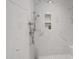 Luxurious walk-in shower with marble tiling, built-in shelving, and modern fixtures for a spa-like experience at 911 Canterbury Rd, Raleigh, NC 27607