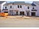 Exterior view of a townhome construction site showing Tyvek HomeWrap, garage doors, and building materials at 1033 Winding Spring Dr, Mebane, NC 27302