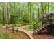 Lush backyard featuring a stone walkway, landscaping, and mature trees, accessible by stairs from a deck at 109 Loch Haven Ln, Cary, NC 27518