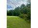 Backyard featuring a green lawn, mature trees, and partial fencing for privacy at 1116 Powder, Fuquay Varina, NC 27526