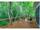 Wooden deck with chairs and railing offers a serene view of the surrounding trees and greenery at 112 Hidden Bluff Ln, Cary, NC 27513