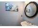 Stylish half bathroom boasts modern fixtures, round mirror, and unique wall art at 11816 Stannary Pl, Raleigh, NC 27613