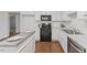 Updated kitchen showcases white cabinets, black appliances, marble countertops, and dark wood floors at 12449 W Pamlico St, Middlesex, NC 27557