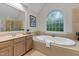 Bright bathroom featuring a soaking tub, large window, and tiled surround at 13121 Sargas St, Raleigh, NC 27614