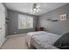 This bedroom has neutral walls with a ceiling fan above a well lit window, complemented by modern furniture and plush carpet at 1420 Norwood Crest Ct, Raleigh, NC 27614