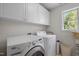 This laundry room has a modern washer and dryer set with upper cabinets providing ample storage space and organization at 1420 Norwood Crest Ct, Raleigh, NC 27614
