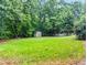 Lush, green backyard with storage shed surrounded by mature trees and open lawn space at 1420 Taylor Farm Rd, Raleigh, NC 27603