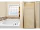 Bright bathroom featuring a soaking tub with decorative tile surround and a glass enclosed shower at 1420 Taylor Farm Rd, Raleigh, NC 27603