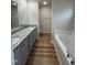 Bright bathroom showcasing double sinks, a granite countertop, wood look floors, and a large soaking tub at 151 Oakfield Trace Dr, Four Oaks, NC 27524