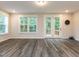 A well lit living room with beautiful floors, large windows, and a glass paneled door leading to a deck at 2008 Van Hook Ln, Apex, NC 27502